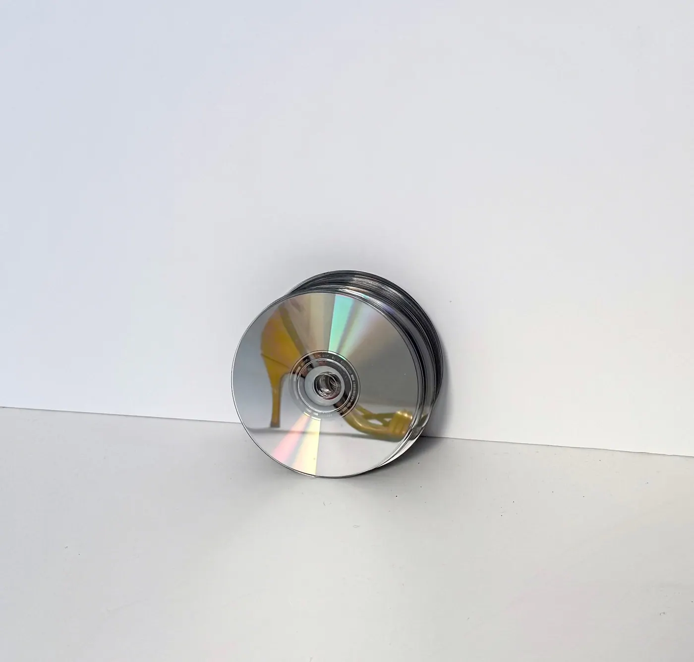 A yellow heel tucked through the hole of a compact disc